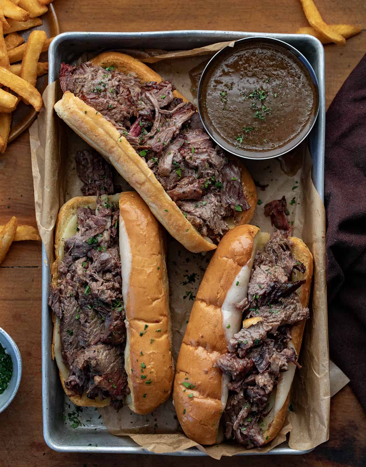 French Dip Sandwiches in a pan with au jus from overhead.