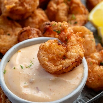 Piece of Fried Shrimp on a bowl of sauce on a plate.
