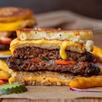 Grilled Cheese Burgers cut in half on a plate with fries.