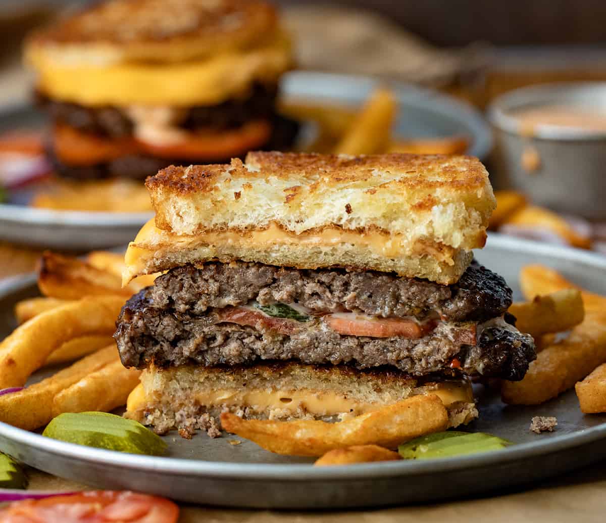 Grilled Cheese Burgers cut in half on a plate with fries.