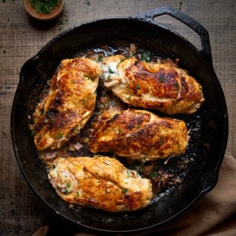 Skillet of Ham and Cheese Stuffed Chicken on a wooden table from overhead.
