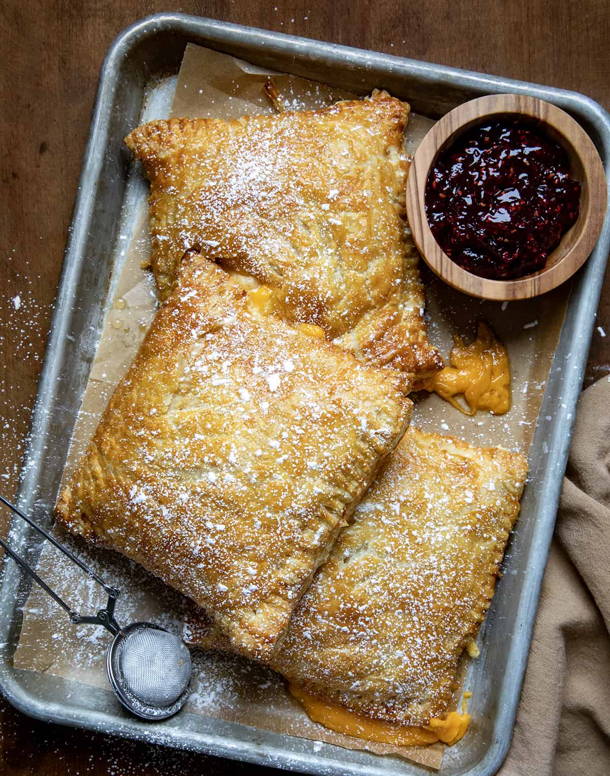 Monte Cristo Puff Pastry in a pan with confectioners sugar and raspberry jam.