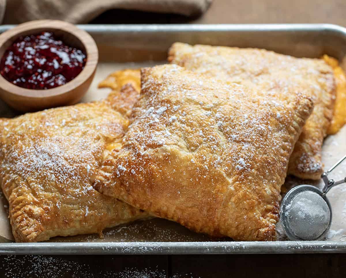 Monte Cristo Puff Pastry in a pan with confectioners sugar and raspberry jam.