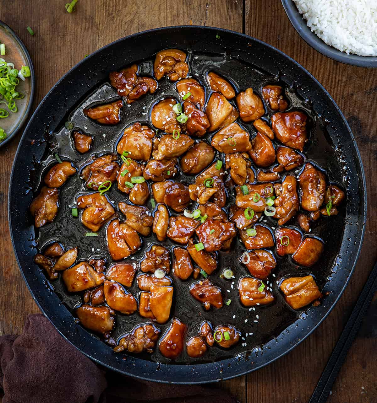Bourbon Chicken in a skillet on a wooden table from overhead.