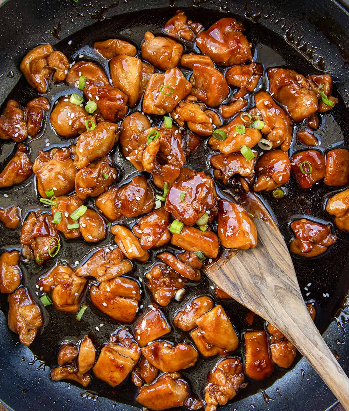 Bourbon Chicken in a black skillet on a wooden table from overhead.