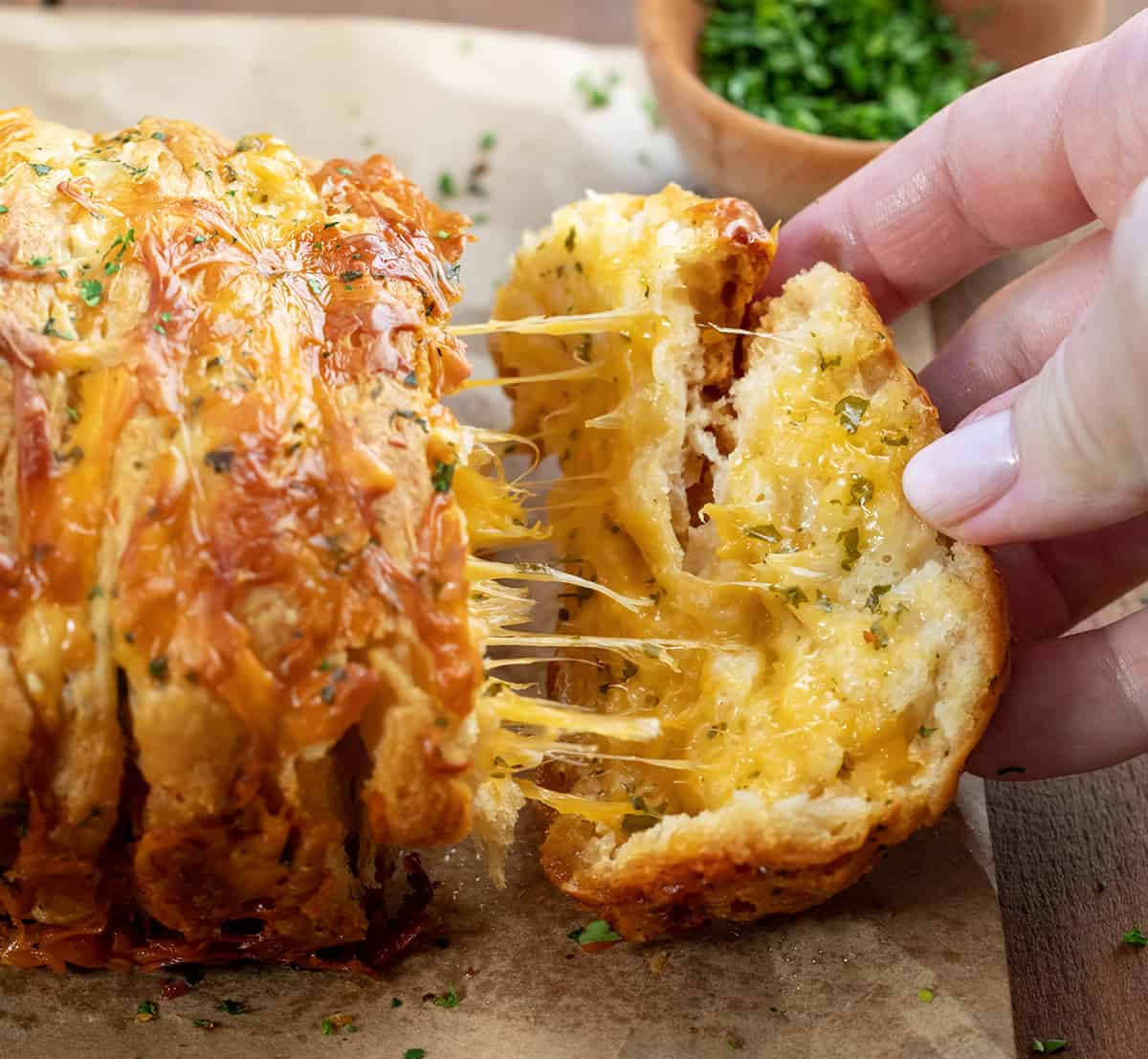 Pulling off a piece of Cheesy Garlic Pull-Apart Bread from the loaf.