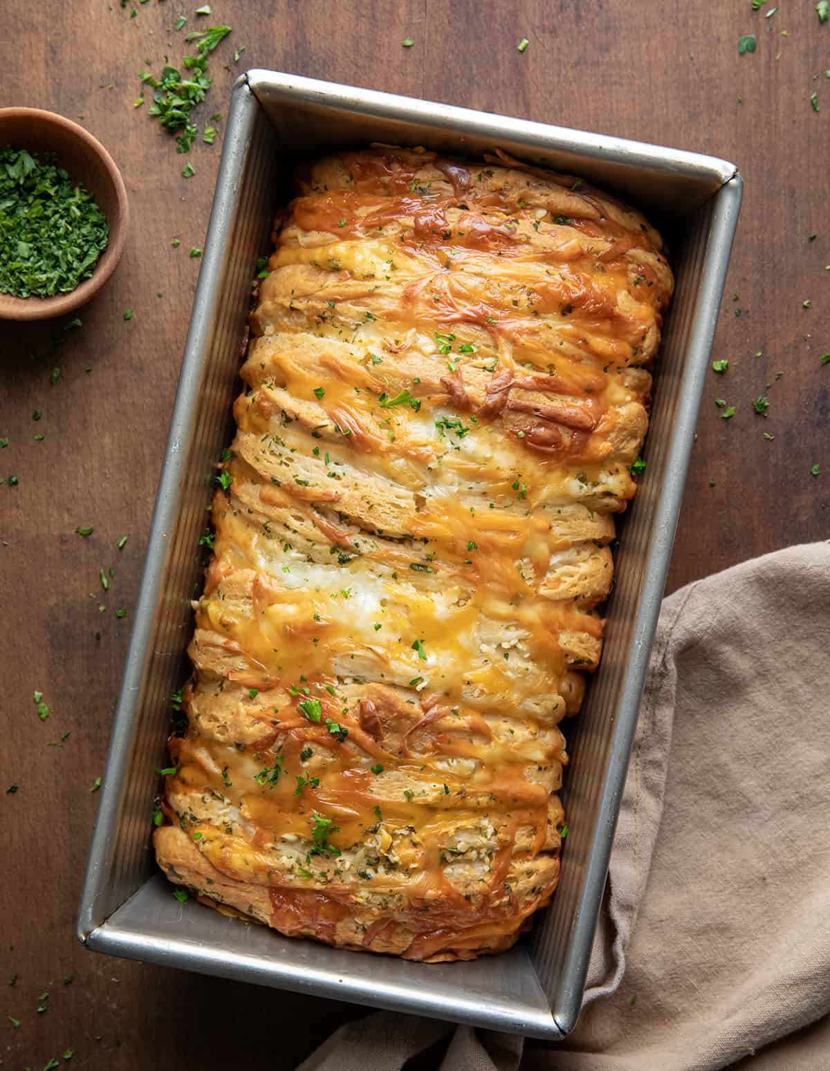 Pan of Cheesy Garlic Pull-Apart Bread on a wooden table from overhead.