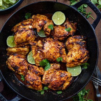 Skillet of Chili Lime Chicken on a wooden table from overhead.