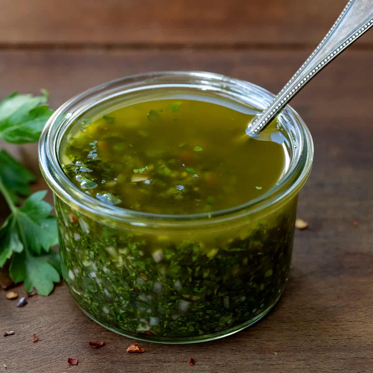 Jar of fresh Chimichurri Sauce with a spoon.