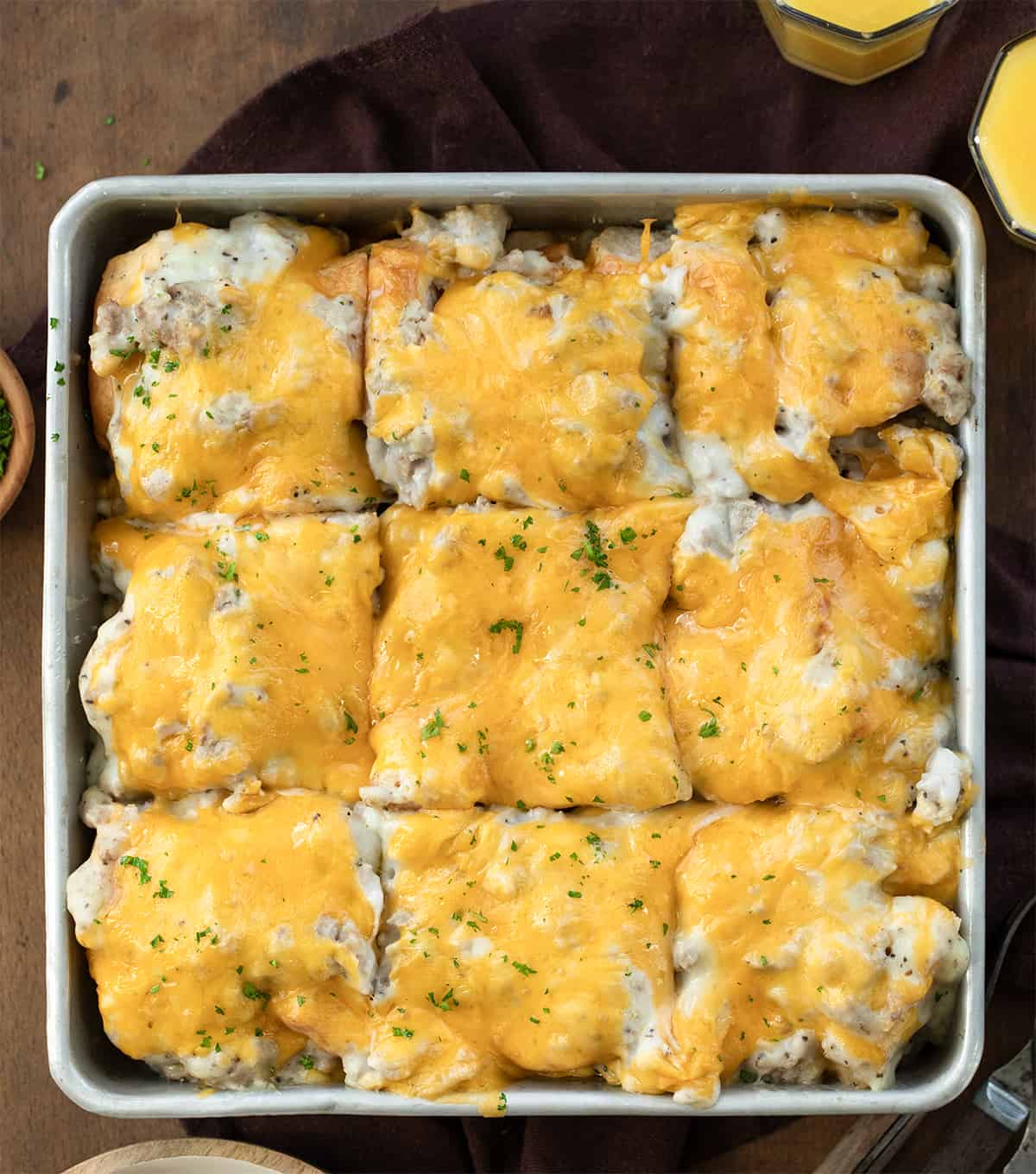 Pan of Easy Biscuits and Gravy Bake cut into pieces on a wooden table from overhead.