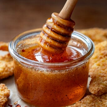 Jar of Hot Honey with a honey dipper picking up honey.