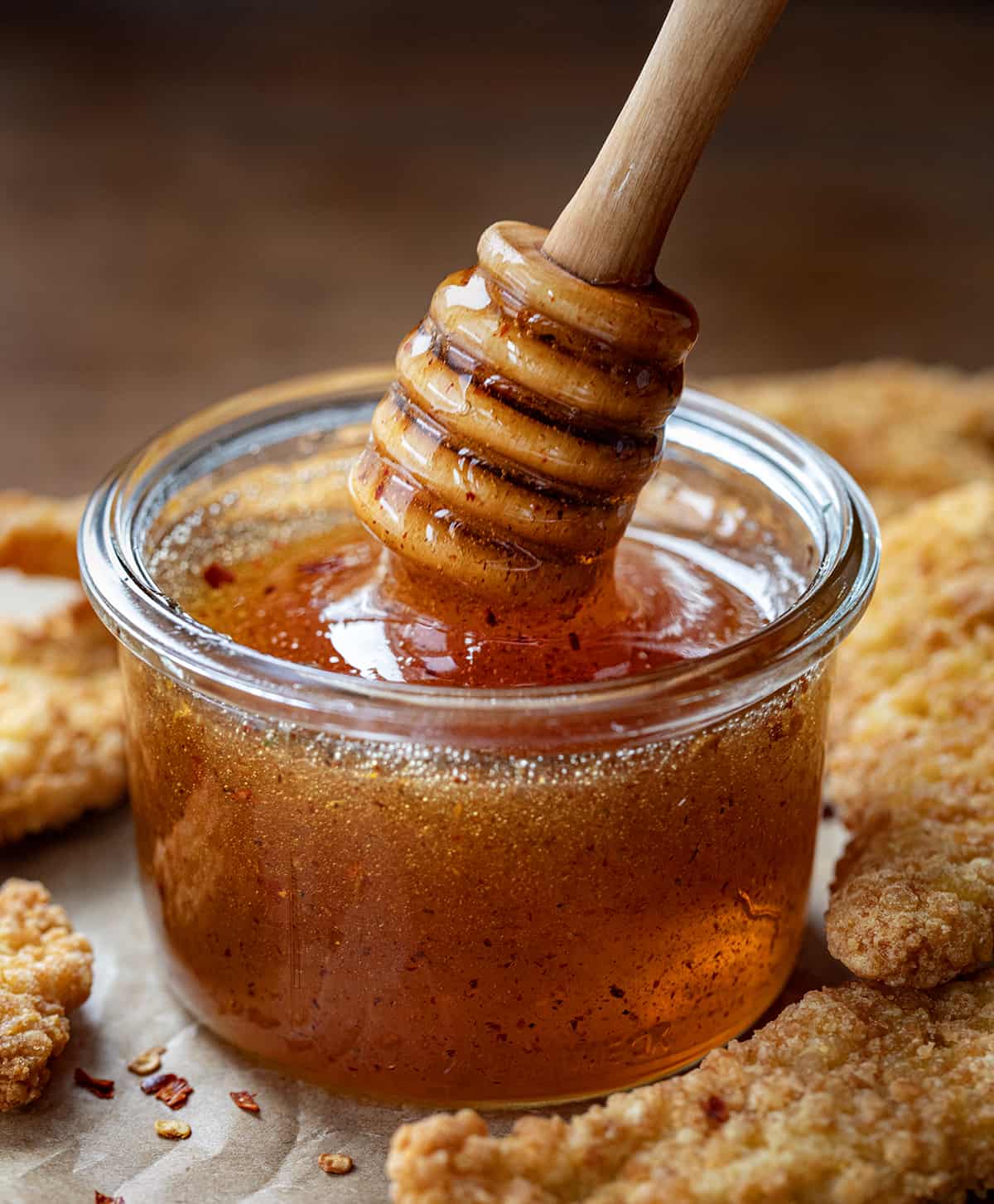 Jar of Hot Honey with a honey dipper picking up honey. 