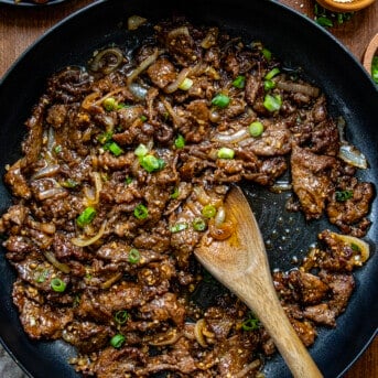 Skillet of Mongolian Beef on a wooden table from overhead.