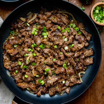 skillet filled with Mongolian Beef on a wooden table from overhead.