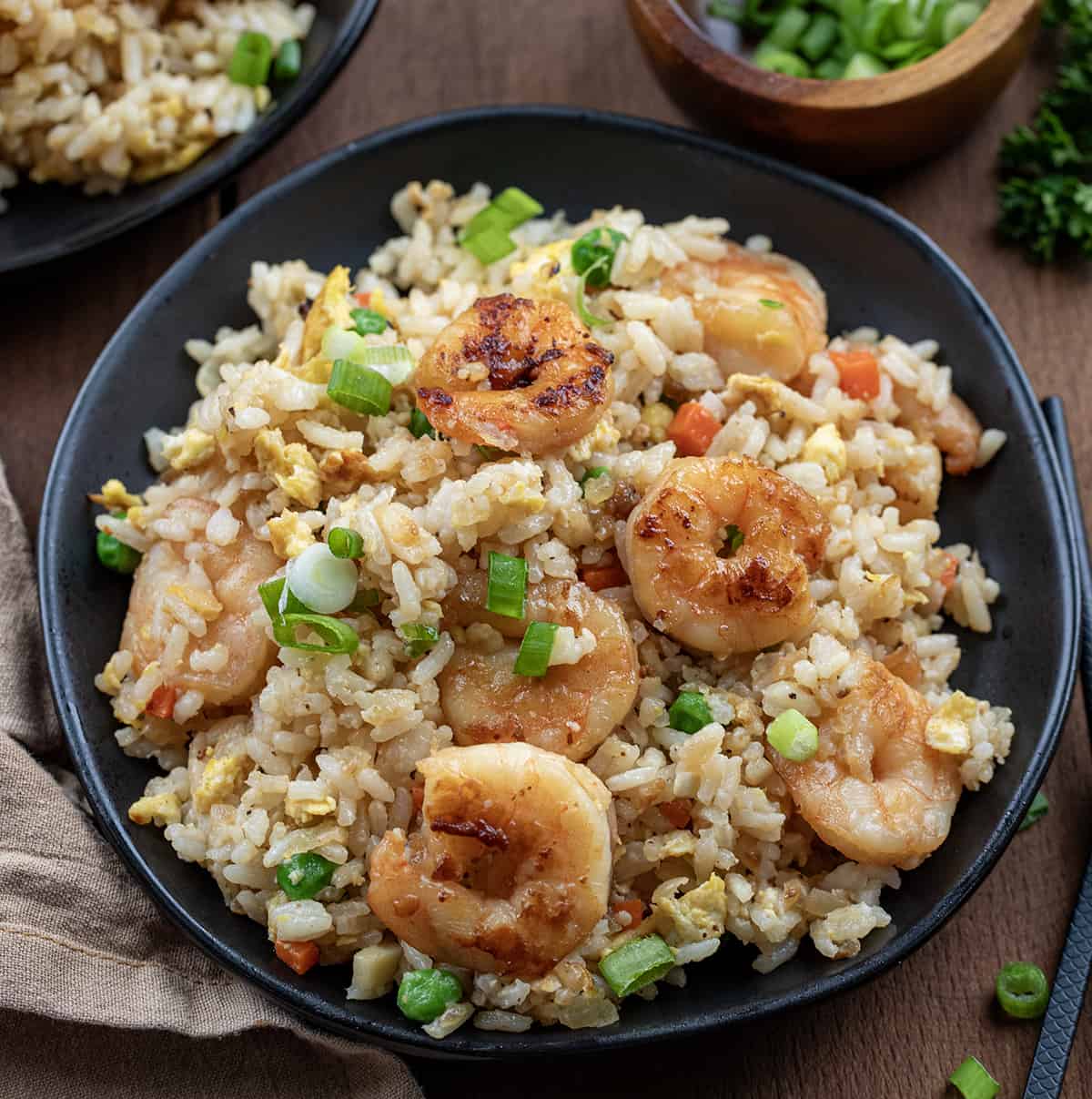 Plates of Shrimp Fried Rice on a wooden table.