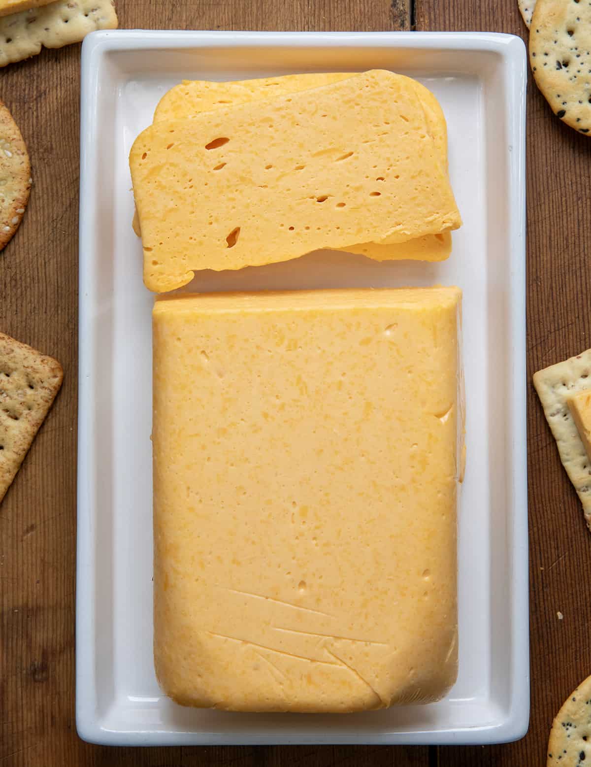 Loaf of Copycat Velveeta Cheese on a platter with a piece cut.