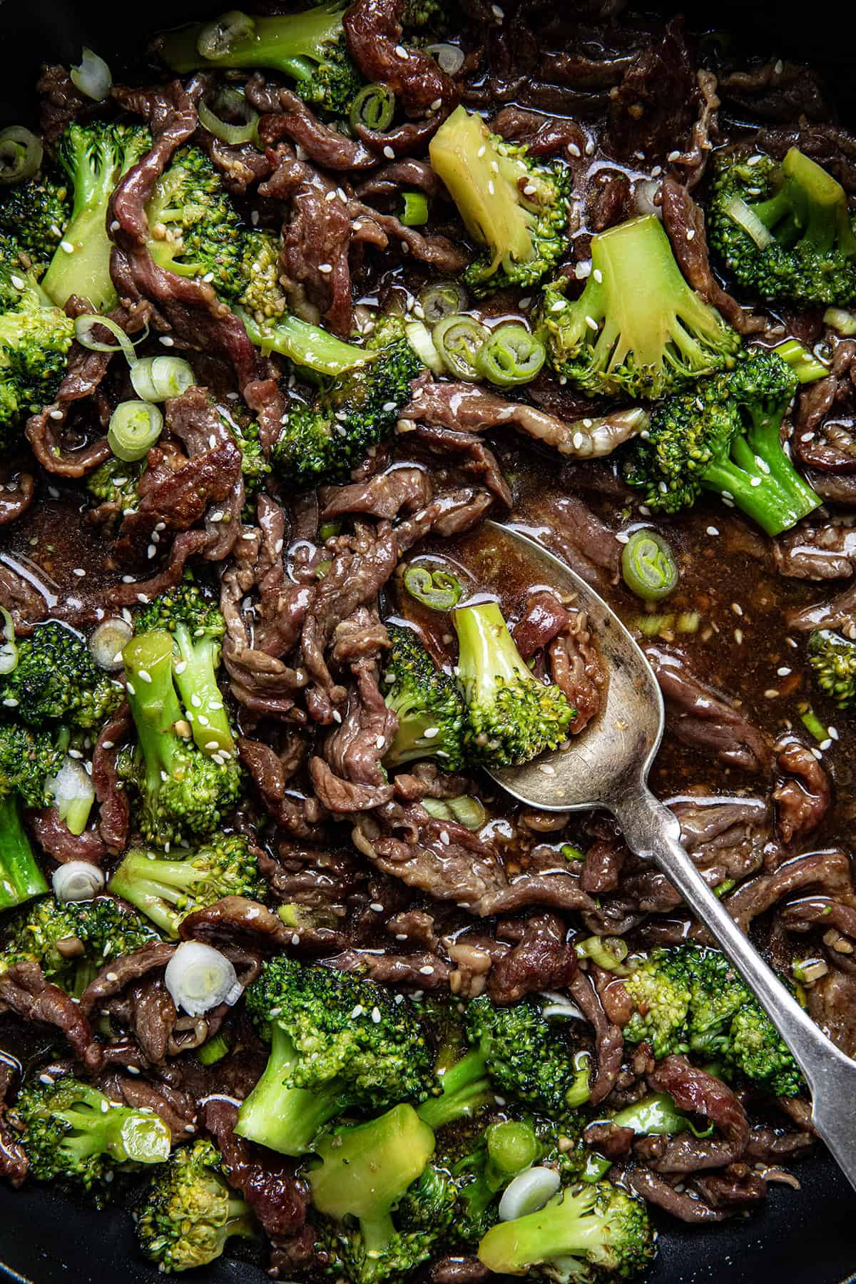 Spoon resting in a pan of Beef and Broccoli.