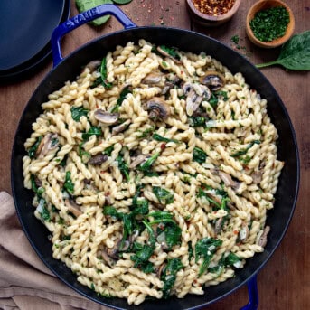 Skillet of Creamy Mushroom and Spinach Pasta on a wooden table from overhead.