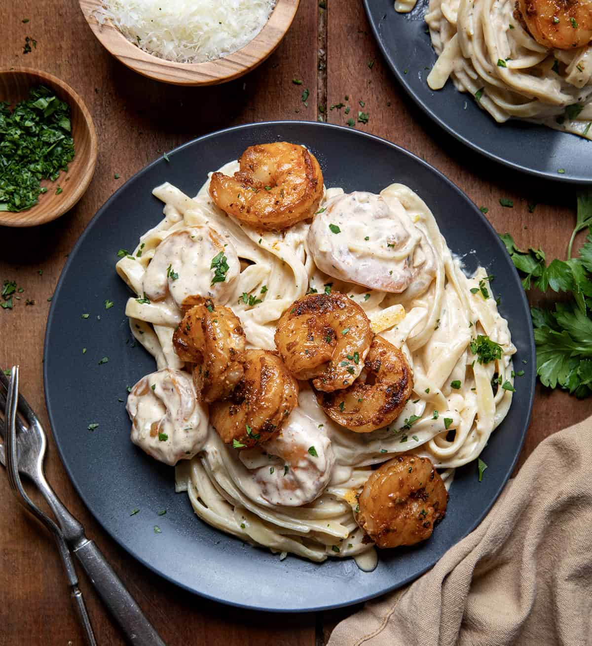 Black plates with Shrimp Alfredo on a wooden table.