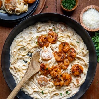 Skillet of Shrimp Alfredo on a wooden table from overhead.