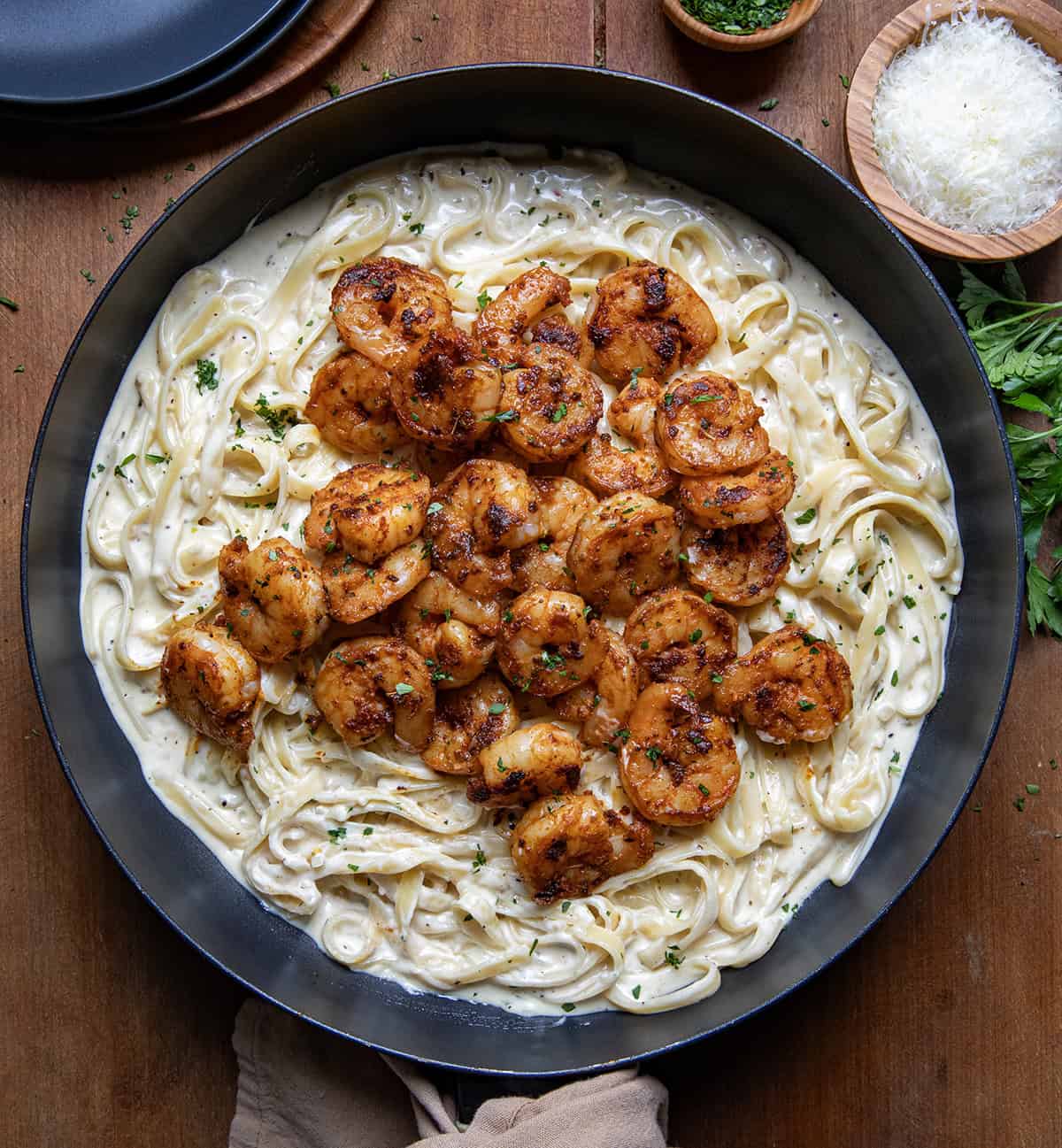Skillet of Shrimp Alfredo on a wooden table from overhead.
