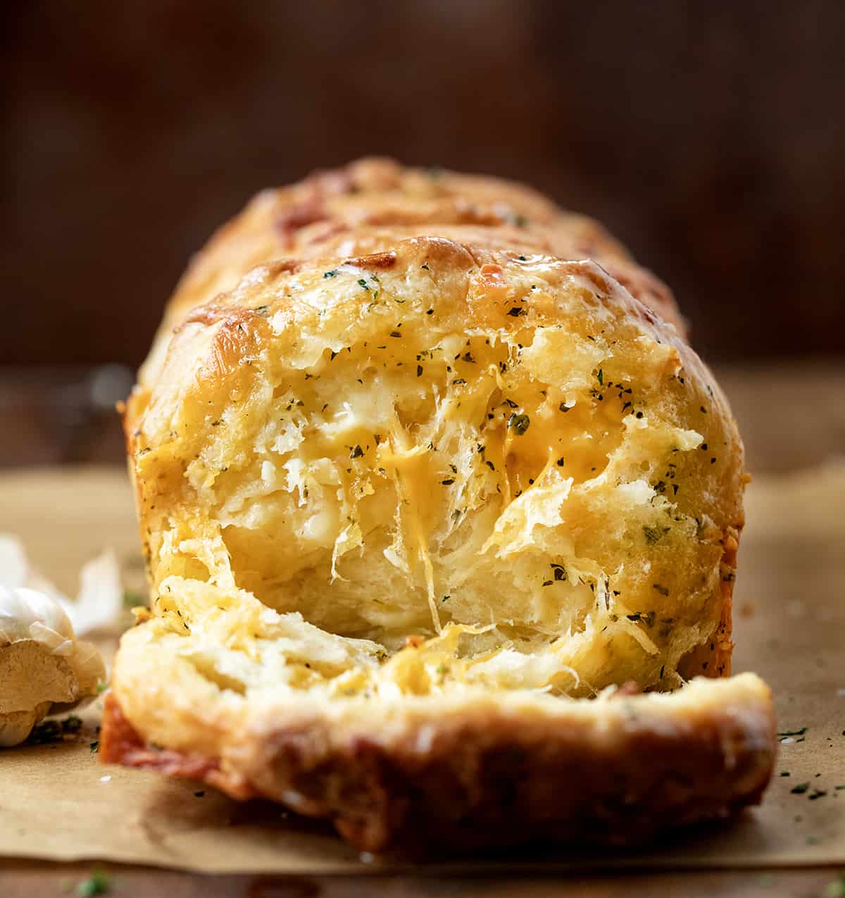 Loaf of From Scratch Cheesy Garlic Pull-Apart Bread with some pieces removed showing inside cheesy tender bread.