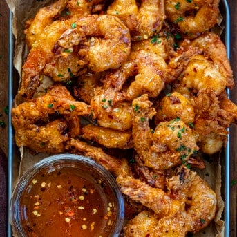 Platter of Hot Honey Fried Shrimp with a jar of hot honey on a wooden table from overhead.