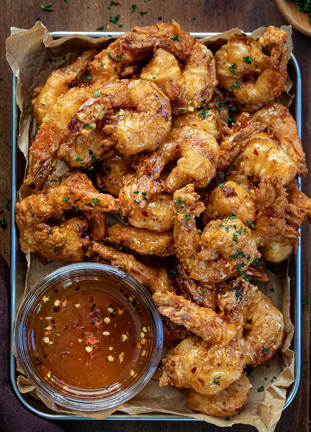 Platter of Hot Honey Fried Shrimp with a jar of hot honey on a wooden table from overhead. 