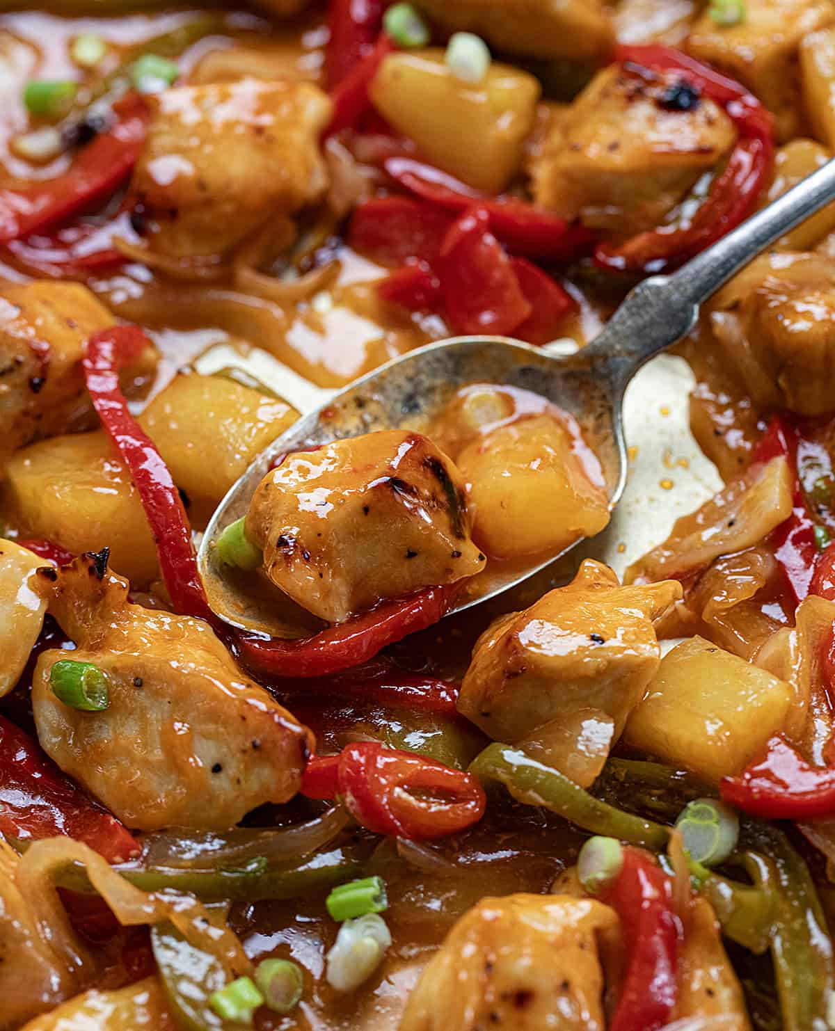 Sweet and Sour Chicken on a Sheet Pan with a spoon picking up some.