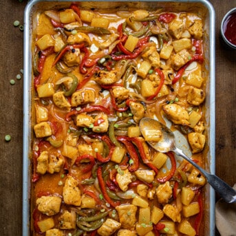 Sweet and Sour Chicken on a Sheet Pan with a spoon picking up some.