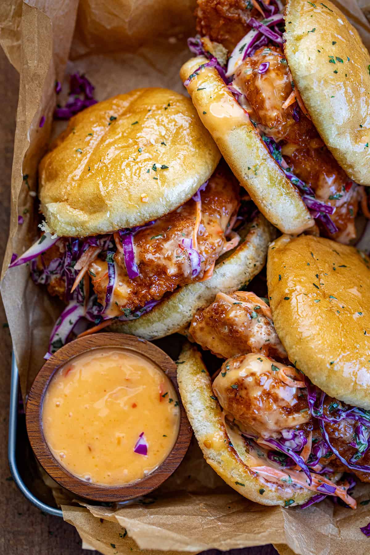 Bang Bang Chicken Sandwiches in a pan on a wooden table from overhead.