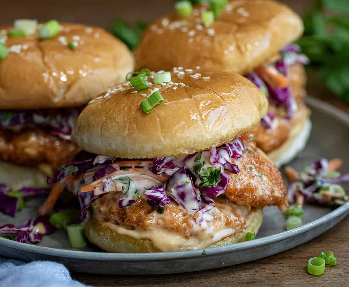 Bang Bang Chicken Sandwiches on a plate on a wooden table close up.
