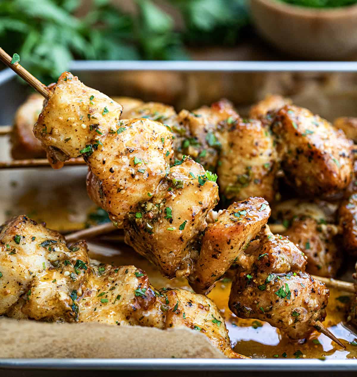 Cowboy Butter Chicken Skewers in a platter with a hold holding one up.