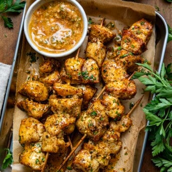 Platter of Cowboy Butter Chicken Skewers next to Cowboy Butter on a wooden table from overhead.