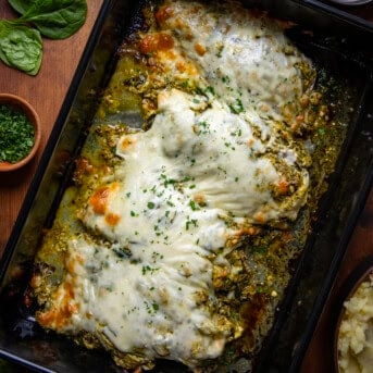 Cheesy Pesto Chicken in a casserole dish on a wooden table from overhead.