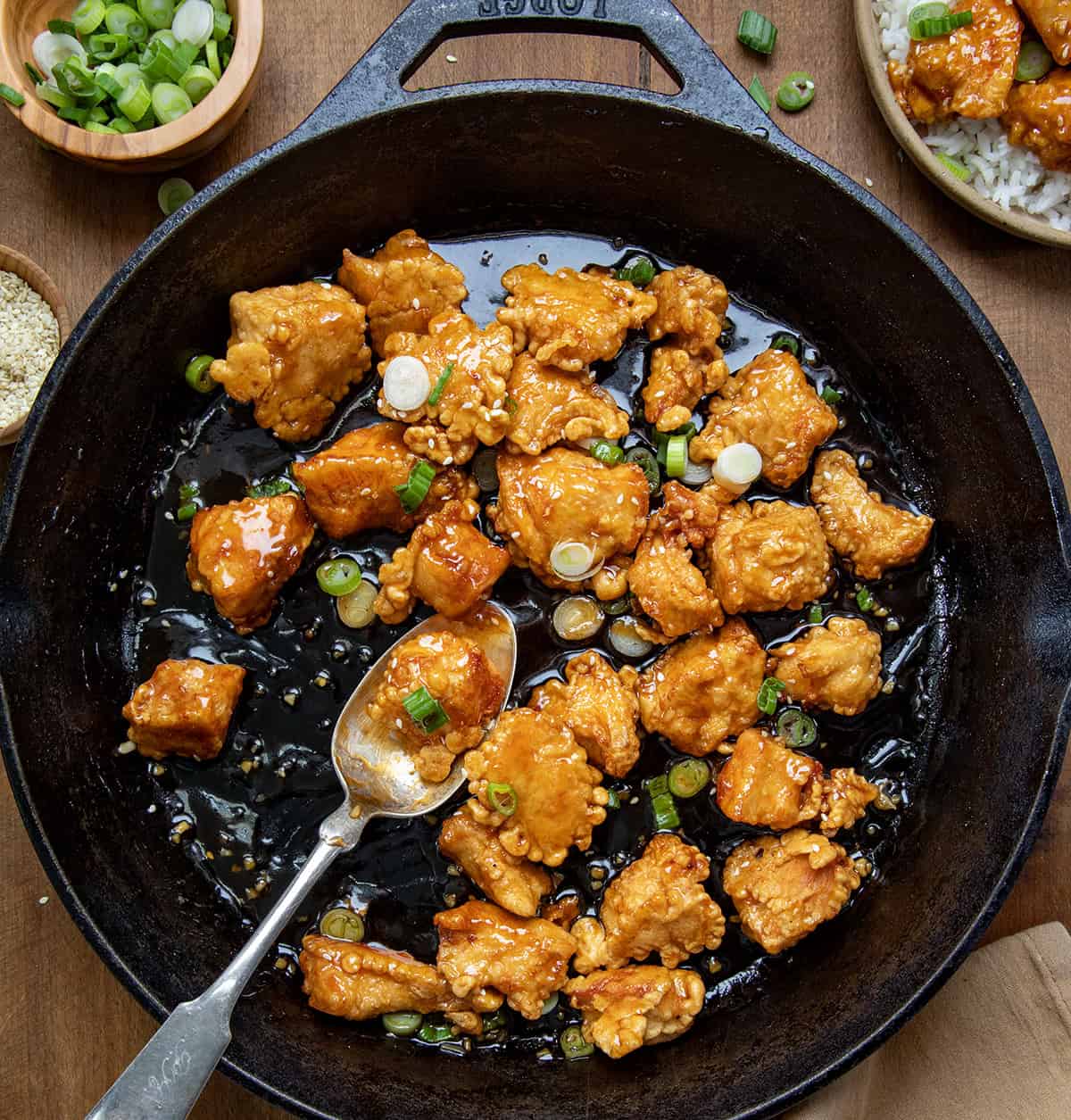 Sesame Chicken in a skillet with a spoon in the skillet from overhead.