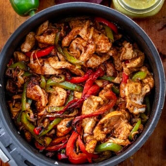 Air Fryer Chicken Fajitas in the air fryer on a wooden table from overhead.