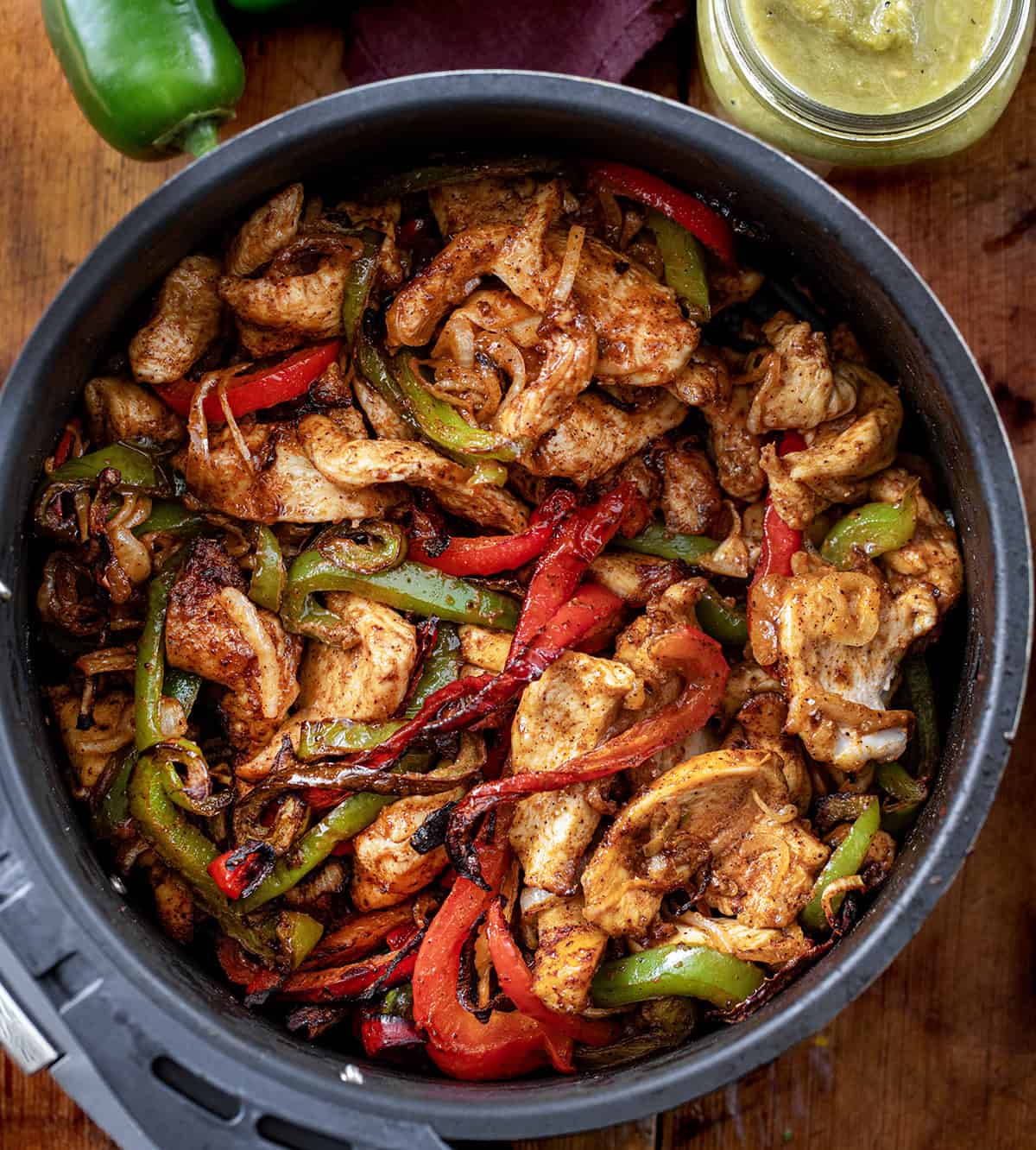 Air Fryer Chicken Fajitas in the air fryer on a wooden table from overhead.