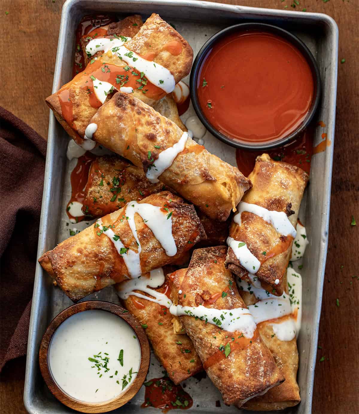 Buffalo Chicken Egg Rolls in a platter on a wooden table from overhead.