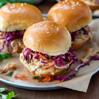 Three Honey Garlic Chicken Sliders on a plate on a wooden table.