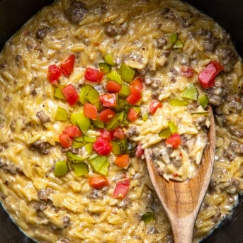 Close up of a pot of Cheeseburger Orzo with a spoon in it showing the creamy texture.