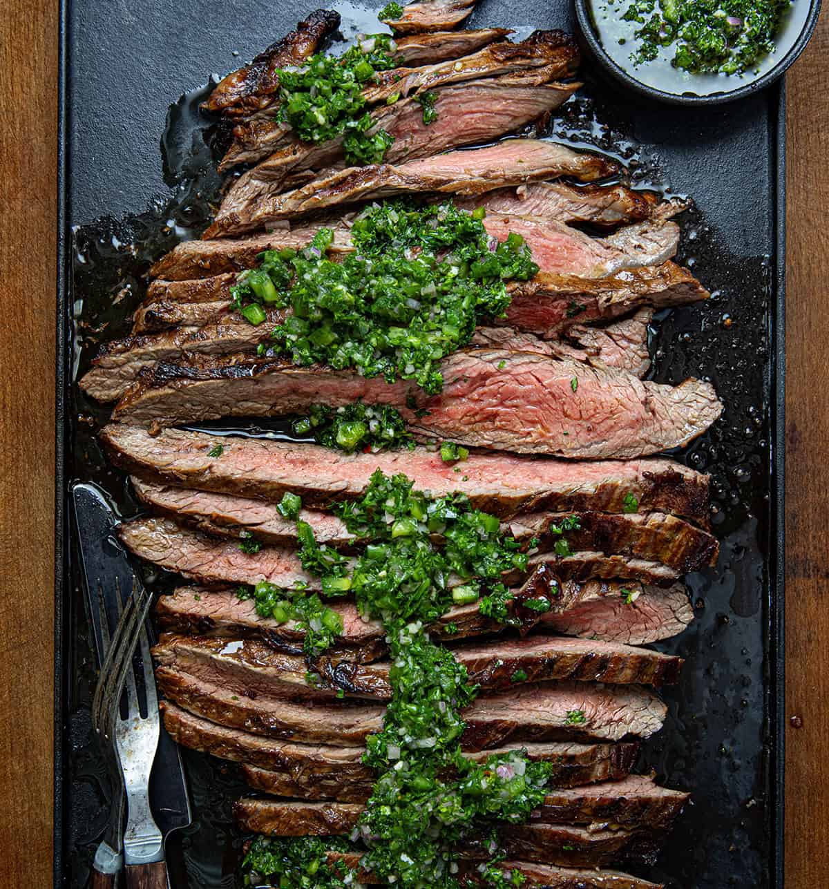 Chimichurri London Broil cut into strips showing tender medium-rare beef covered in chimichurri sauce.