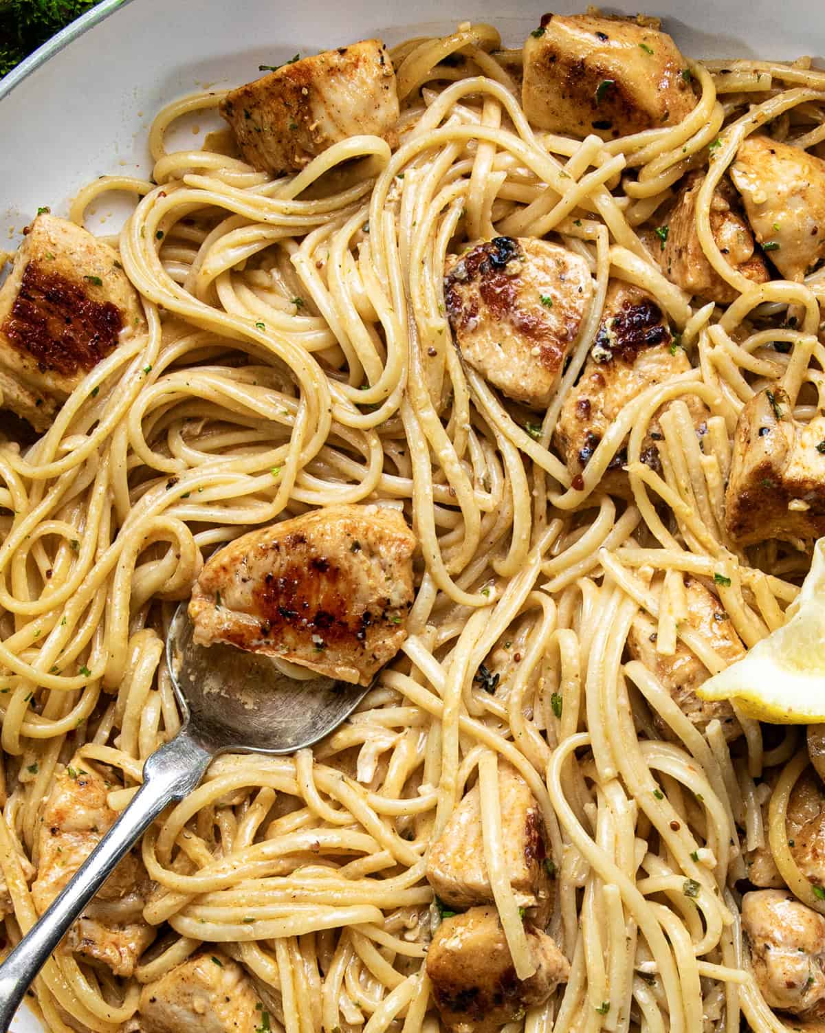 Close up of creamy cowboy butter pasta with a spoon holding a chicken bite.