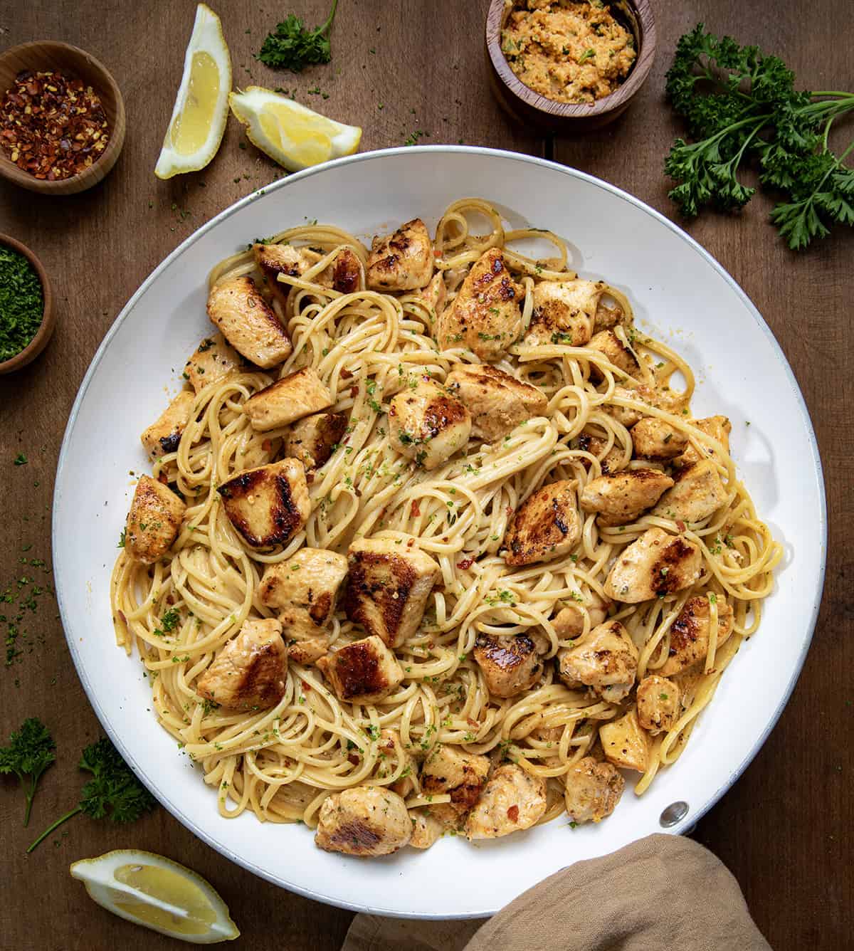 Cowboy Butter Chicken Linguine in a skillet on a wooden table next to cowboy butter from overhead.