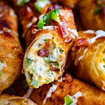 Jalapeno Popper Egg Rolls together and the center egg roll is cut showing the filling inside.