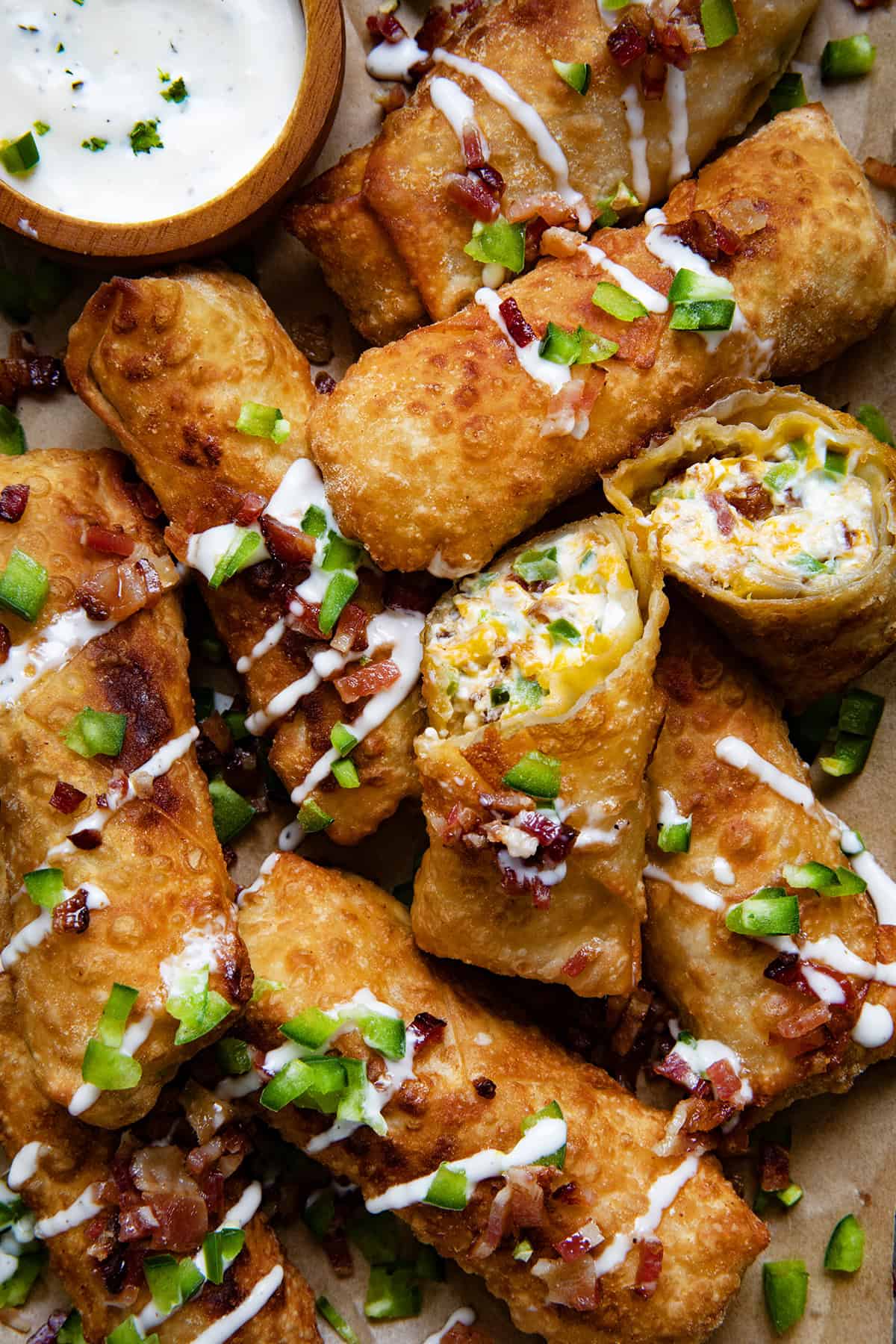 Jalapeno Popper Egg Rolls together and the center egg roll is cut showing the filling inside.