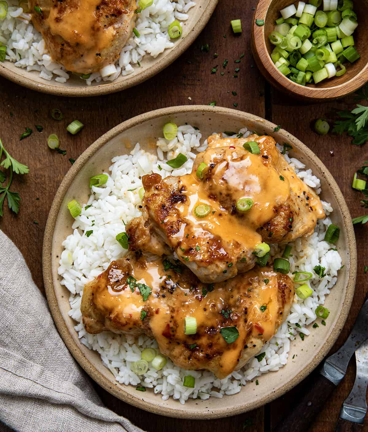 Plates with Bang Bang Chicken Thighs on them on a bed of rice from overhead.