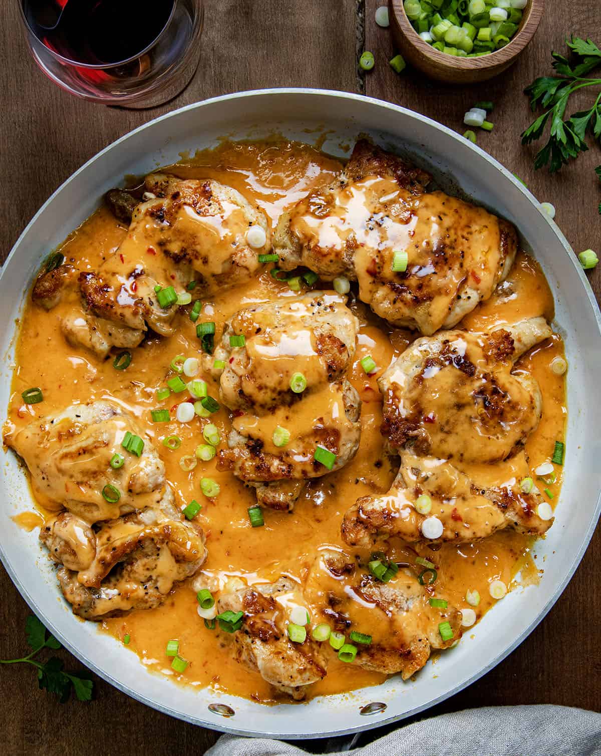 Skillet of Bang Bang Chicken Thighs on a wooden table from overhead. 