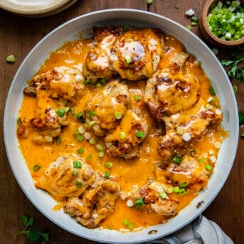 Skillet of Bang Bang Chicken Thighs on a wooden table from overhead.