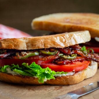 Whole Spicy Candied Bacon BLT on a cutting board.